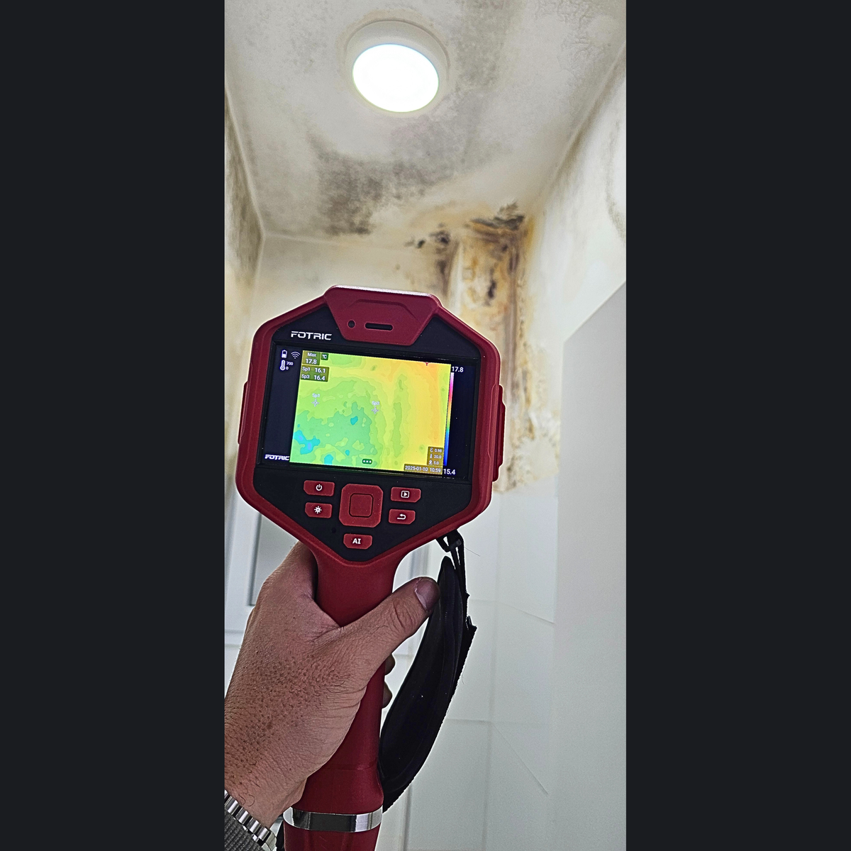 בודק אוחז מצלמה תרמית FOTRIC ומצלם פינת תקרה עם רטיבות